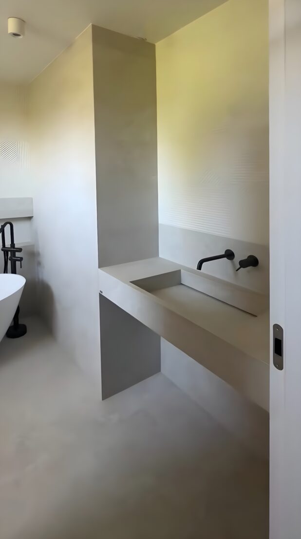 Un baño de estética industrial y sensibilidad cálida en el que la grifería empotrada de IMEX refuerza la pureza del diseño y la funcionalidad del espacio.